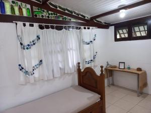 a bedroom with a bed and a table and a window at Loft dos Vagalumes in Boicucanga