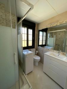 a bathroom with a toilet and a sink and a mirror at Vivienda Turística Playa Vida Punta Umbría in Punta Umbría