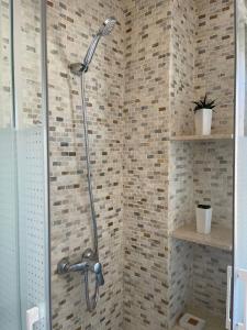 a shower in a bathroom with a brick wall at Vivienda Turística Playa Vida Punta Umbría in Punta Umbría +3 photos