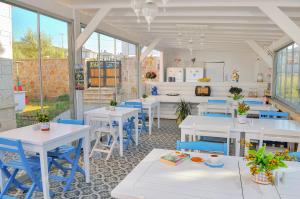 a restaurant with white tables and blue chairs at Allegria Butik Otel in Ildır