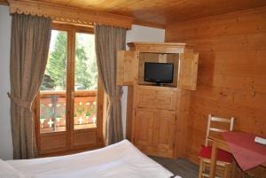 um quarto com uma cama, uma televisão e uma janela em Oustalet em Chamonix-Mont-Blanc