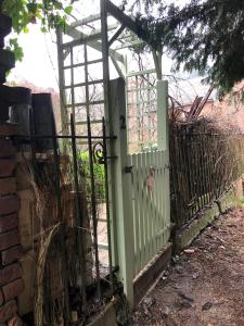 a green gate in a fence next to a brick wall at Mingo Cottage in Bewdley