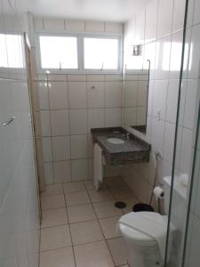 a bathroom with a toilet and a sink and a window at Habitat Hotel de Leme Ltda in Leme