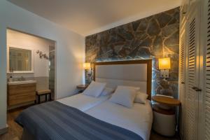 a bedroom with a bed and a stone wall at CASA RURAL EL ESQUILON TENERIFE in La Orotava