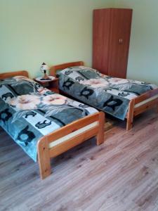 two twin beds in a room with wood floors at Pokoje Pod Łukami in Solina