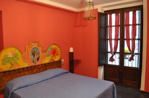 a bedroom with orange walls and a bed and a window at Foresteria dell'Alloro in Palermo