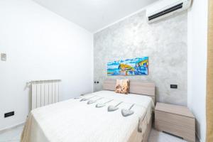 イスキアにあるTra centro e mareの白いベッドルーム(大型ベッド1台付)が備わります。壁には絵画が飾られています。