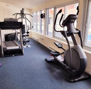 une salle de sport avec deux tapis de course et un tapis roulant dans l'établissement Hotel et Motel Le Chateauguay, à Québec