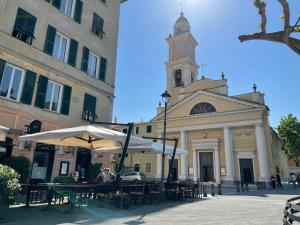 een gebouw met een klokkentoren en tafels met parasols bij Santa d'aMare appartamento con terrazzo e box auto privato in Santa Margherita Ligure