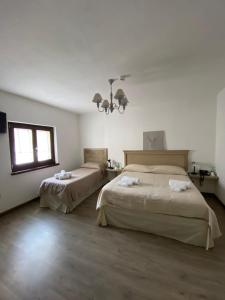 a bedroom with two beds and a window and a chandelier at HOTEL CAMPO STELLA in Leonessa