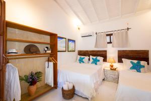 2 Betten in einem Zimmer mit weißen Wänden und blauen Kissen in der Unterkunft Pousada Jequitibá in Trancoso