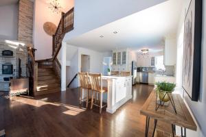 a kitchen and living room with a staircase and a table at La Maison Laurentienne, Vue sur le fleuve ,Spa et Sauna in Sainte-Famille