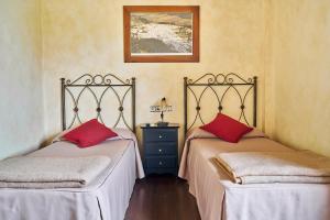 2 camas en una habitación con almohadas rojas. en El Mirador del Valle, en San José del Valle