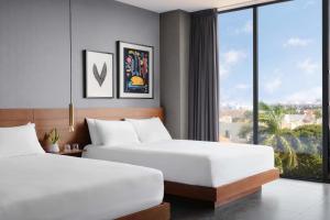 two beds in a hotel room with a large window at MARQUEE Playa Hotel in Playa del Carmen +19 photos