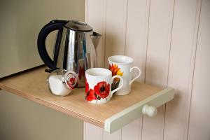 グレート・ドリフフィールドにあるMill Farm Shepherds Hutの木製の棚に座ったコーヒーカップ2杯