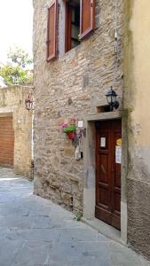 a stone building with a wooden door and a window at Le Residenze Ristori in Cortona