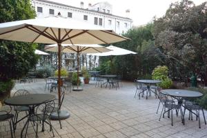 eine Außenterrasse mit Tischen, Stühlen und Sonnenschirmen in der Unterkunft Hotel Belle Arti in Venedig