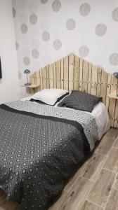 een slaapkamer met een groot bed met een houten hoofdeinde bij Les Fauvettes in Pontorson