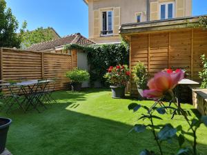 un jardín con una valla de madera, una mesa y flores en La Maison V.H., Appartements d'Hôtes, en Troyes