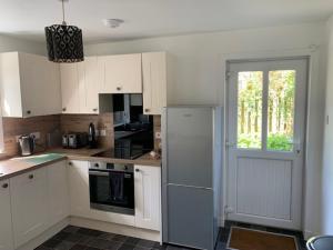 a kitchen with white cabinets and a refrigerator at Victoria Cottage, 8 Victoria Road in Orkney