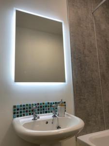 a white bathroom with a sink and a mirror at Victoria Cottage, 8 Victoria Road in Orkney