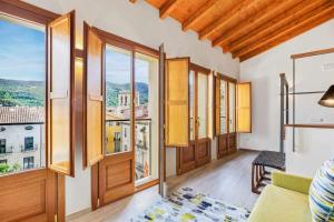 Can Bona Casa Dúplex con terraza في بيسالو: غرفة معيشة مع نوافذ كبيرة وأريكة