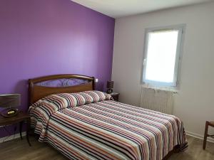 a bedroom with purple walls and a bed with a striped bedspread at Appartement Cambo-les-Bains, 2 pièces, 2 personnes - FR-1-495-74 in Cambo-les-Bains