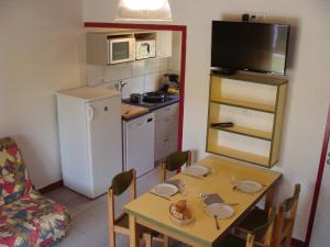 eine kleine Küche mit einem Tisch und eine kleine Küche mit einem Kühlschrank in der Unterkunft Résidence de Tourisme LE VENDAHAUT in Lapleau