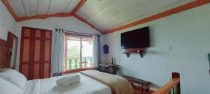 a bedroom with a bed and a flat screen tv at Pousada Solar dos Anjos in Lavras Novas