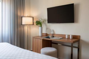 una camera d'albergo con scrivania, TV e letto di Doria Park Hotel a Lerici