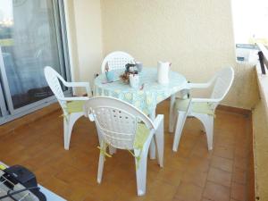 uma mesa com cadeiras brancas e uma mesa e uma mesa e cadeiras em Studio Marseillan-Plage, 1 pièce, 4 personnes - FR-1-387-137 em Marseillan