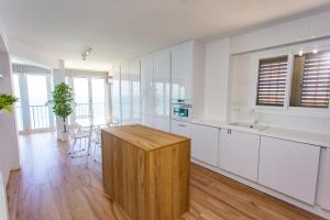 a kitchen with white cabinets and a wooden island at Cullera Panoramic Sea Views Apartment in Cullera