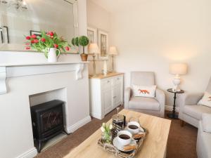 a living room with a fireplace and a table at Foxy Cottage in Harrogate