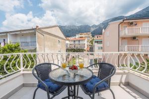 a balcony with a table and two glasses of orange juice at Apartman MG Makarska in Makarska
