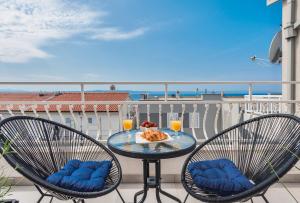 een tafel met 2 stoelen op een balkon met uitzicht op de oceaan bij Apartman MG Makarska in Makarska