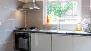 a kitchen with white cabinets and a sink and a window at Bevington House - Air Host & Stay - 3 Bedroom Close to City Centre in Liverpool +30 photos