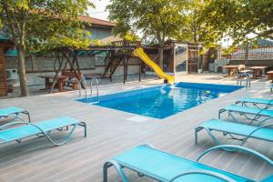una piscina con tobogán y bancos azules y un parque infantil en Guest House Nevena, en Shabla