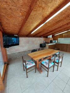 a wooden table and chairs in a kitchen with a tv at Guest House Nevena in Shabla