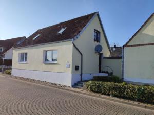 a white house with a black roof on a street at Zum Boddenblick in Breege