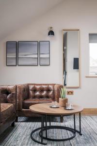 a living room with a brown leather couch and a table at The Blind Bull in Little Hucklow