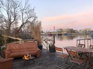 a couch and a table on a deck next to the water at Hausboot mit Hottub in Berlin in Berlin