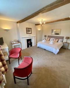 a bedroom with a bed and two chairs and a fireplace at Antlers Bed and Breakfast in Abbots Bromley