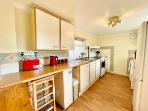 cocina con armarios blancos y suelo de madera en The Cottage en York