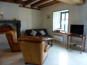 a living room with a couch and a chair and a television at Gîte Louchy-Montfand, 3 pièces, 4 personnes - FR-1-489-178 in Louchy-Montfand