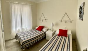 two beds in a small room with red pillows at APARTAMENT GRIFEU in Llança