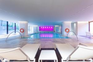 a pool with white chairs and a swimming pool at Royal Hideaway Sancti Petri in Chiclana de la Frontera