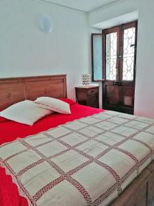Schlafzimmer mit einem Bett mit roter Bettwäsche und einem Fenster in der Unterkunft Appartamento Cristina in Stresa
