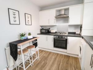 a kitchen with white cabinets and a counter with stools at Marden Mews in Whitley Bay