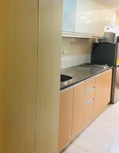 a kitchen with brown cabinets and a black refrigerator at Josh's Place at One Eastwood Avenue Tower 1 in Manila