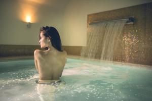 a woman in a swimming pool with a shower at Hotel Palazzo San Lorenzo & Spa in Colle Val D'Elsa
